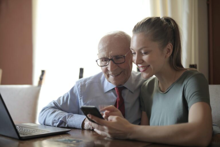 Older man and woman smiling at phone in Canada after immigrating