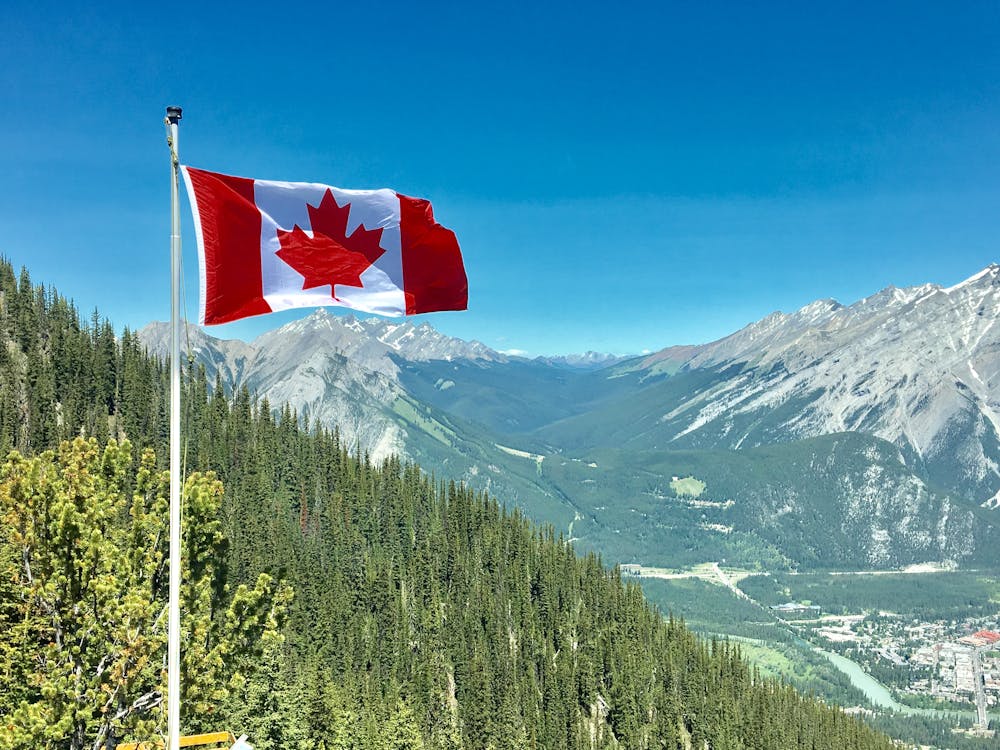 Canada flag raised above mountains